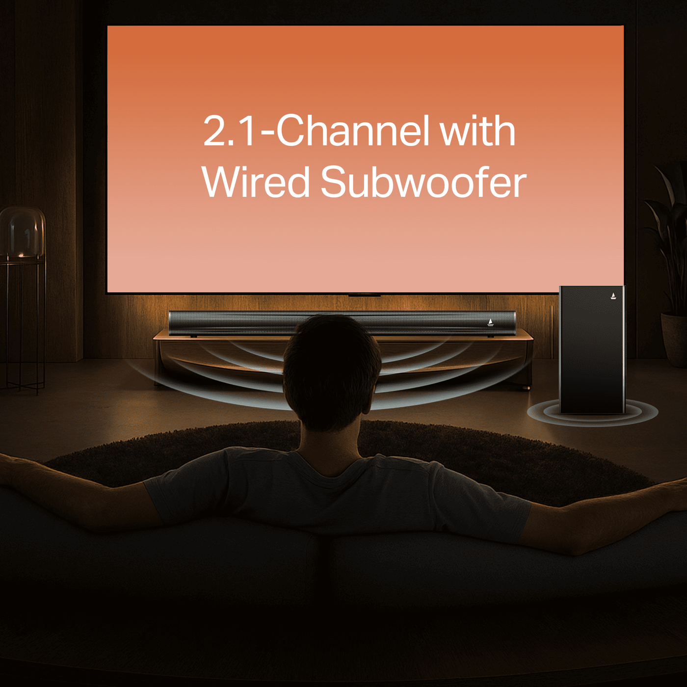 Man watching large TV with 2.1-channel soundbar and wired subwoofer in modern home