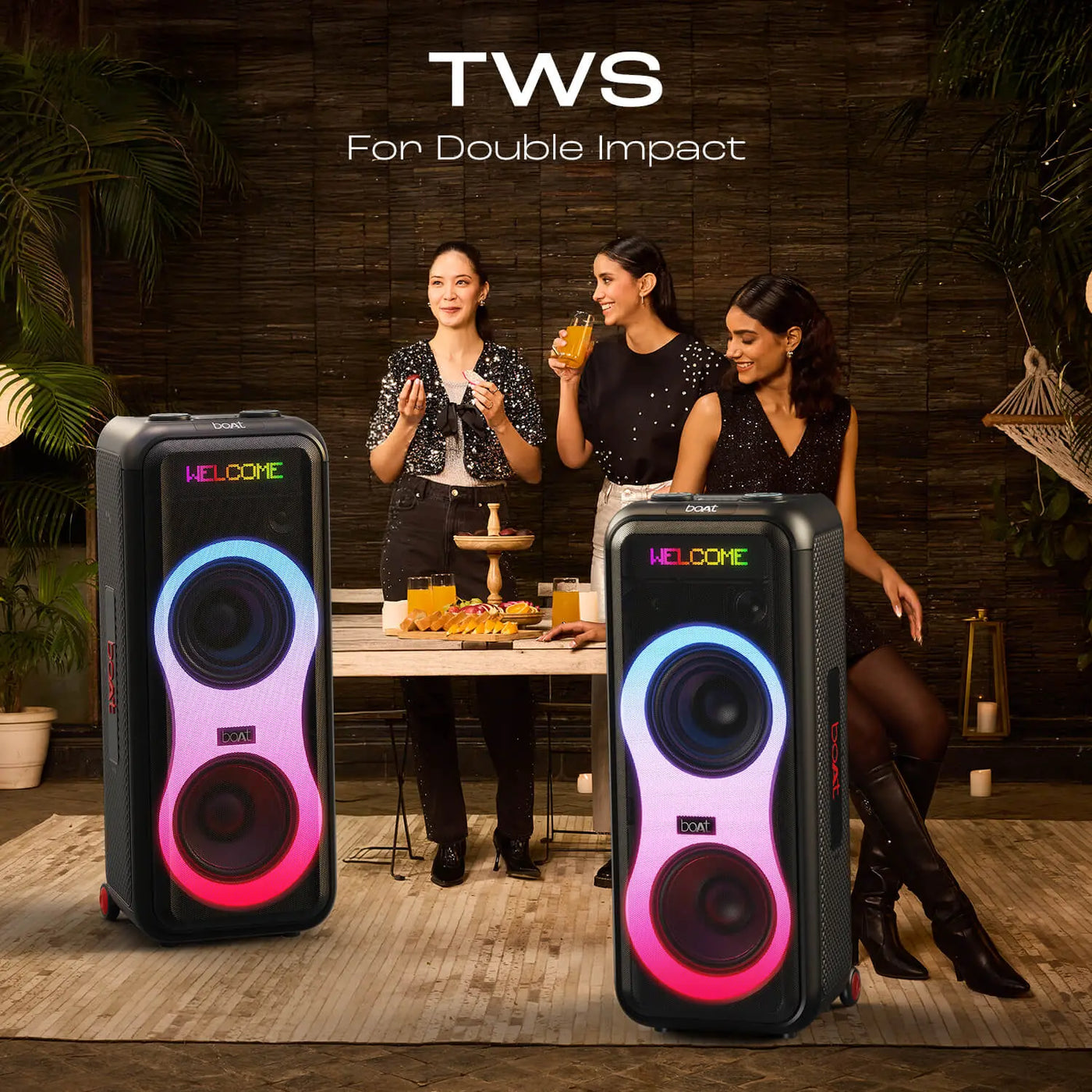 Party scene with three women, snacks, drinks, and two boAt TWS speakers with LED lights